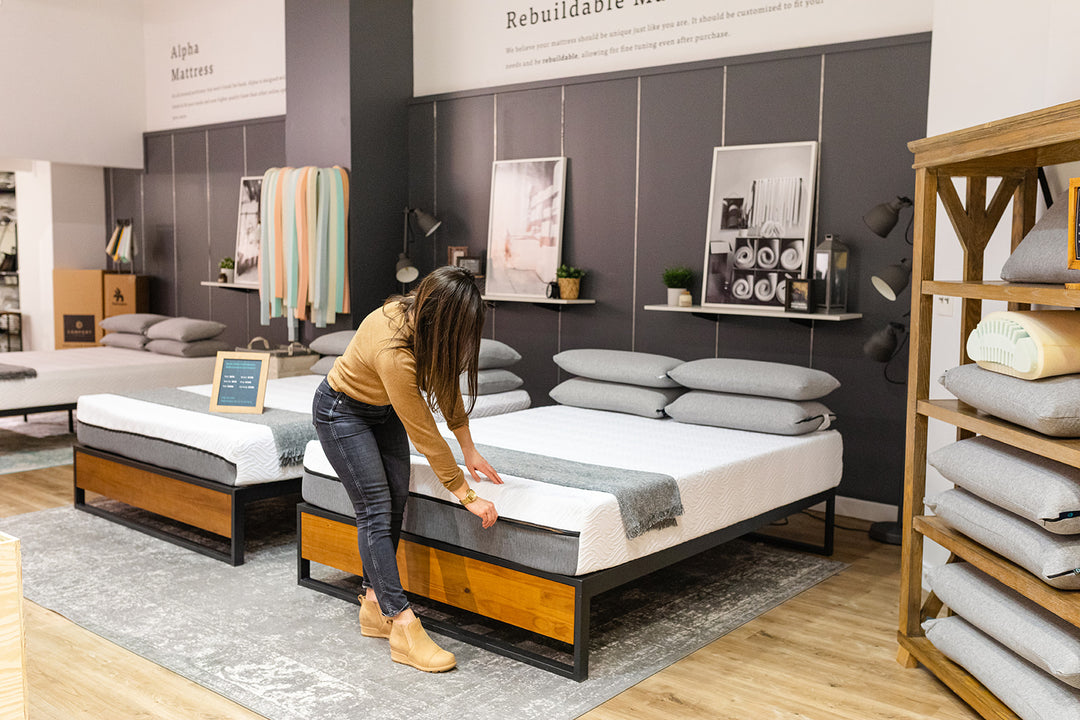 Image of a woman touching a mattress in COmfort Option Store