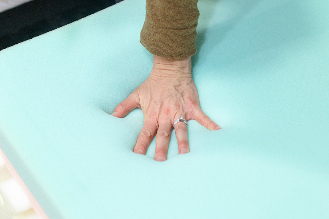 Image of hand touching a foam mattress