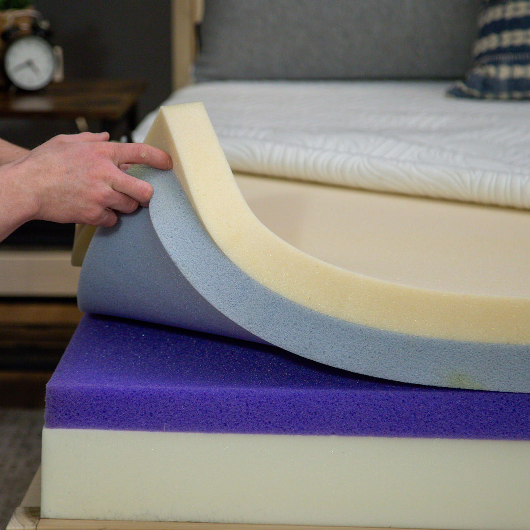 A photo of hands moving layers on a mattress