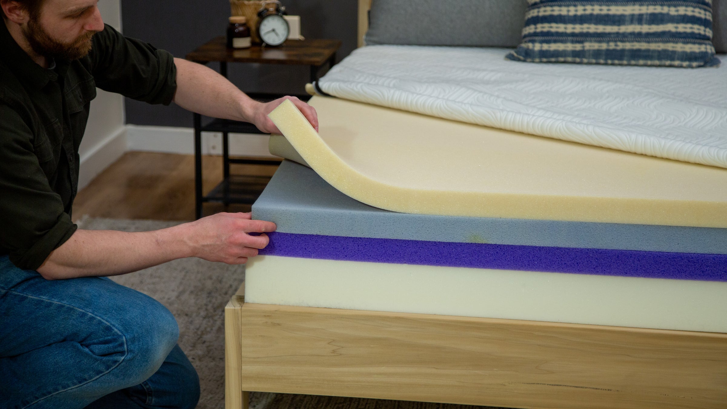 A lifestyle photo of a man moving foam layers on the inside of a mattress