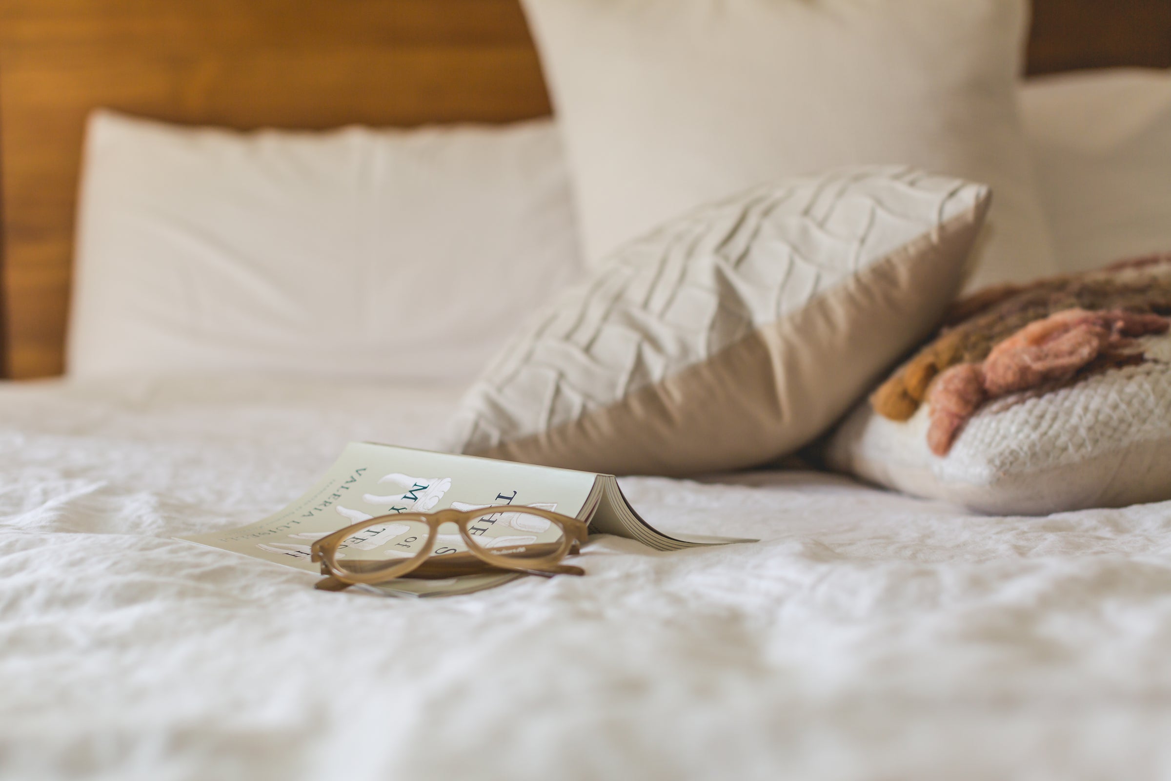 photo of glasses and a book on a bed