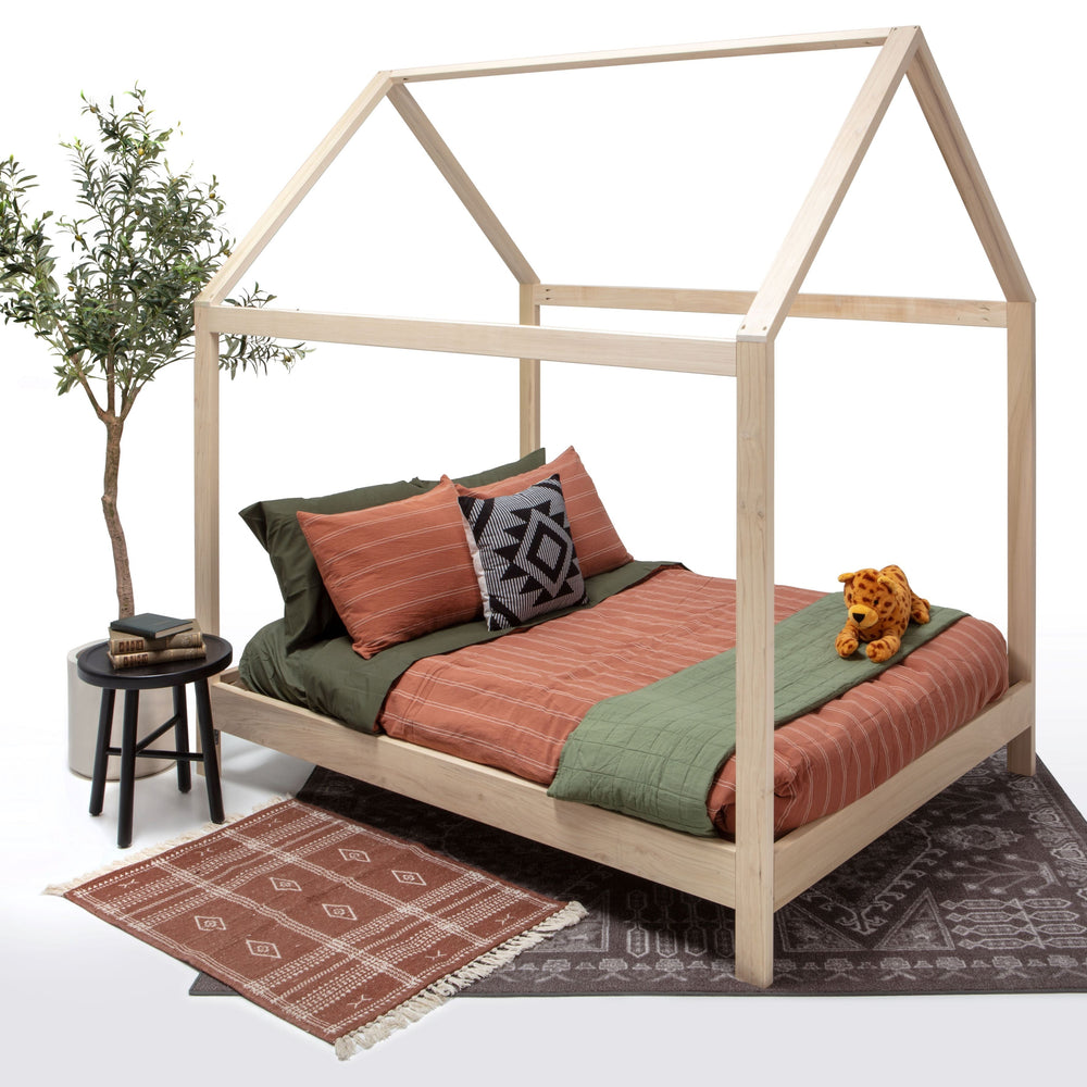 Wooden children's bed with bedding and a plant on a white background