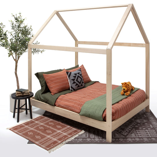 Wooden children's bed with bedding and a plant on a white background