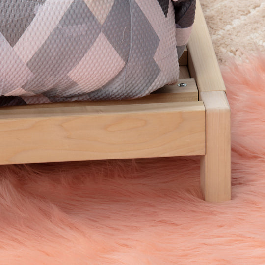 Wooden bed frame on a pink fluffy rug