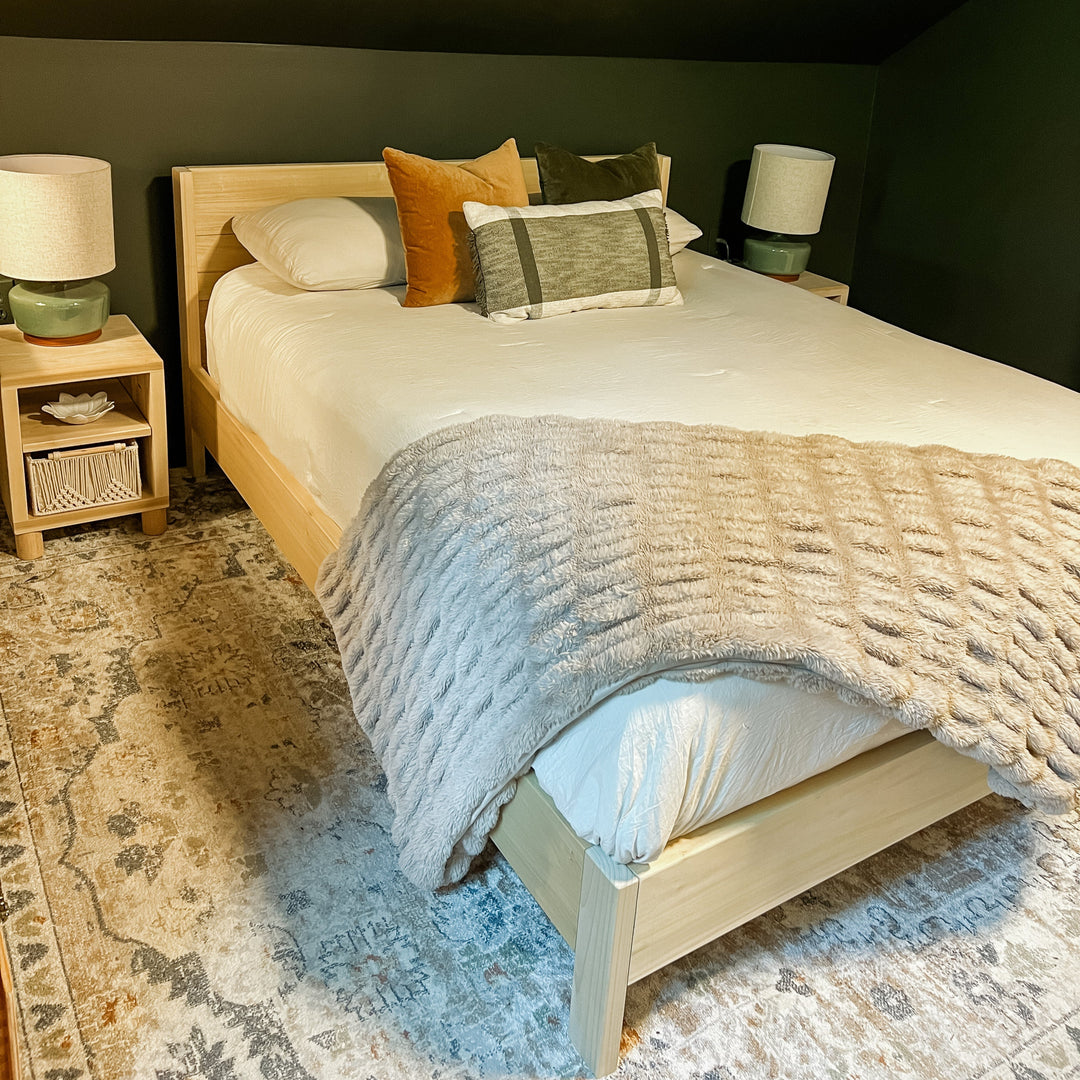Bedroom with a bed, nightstands, and lamps against a dark wall.