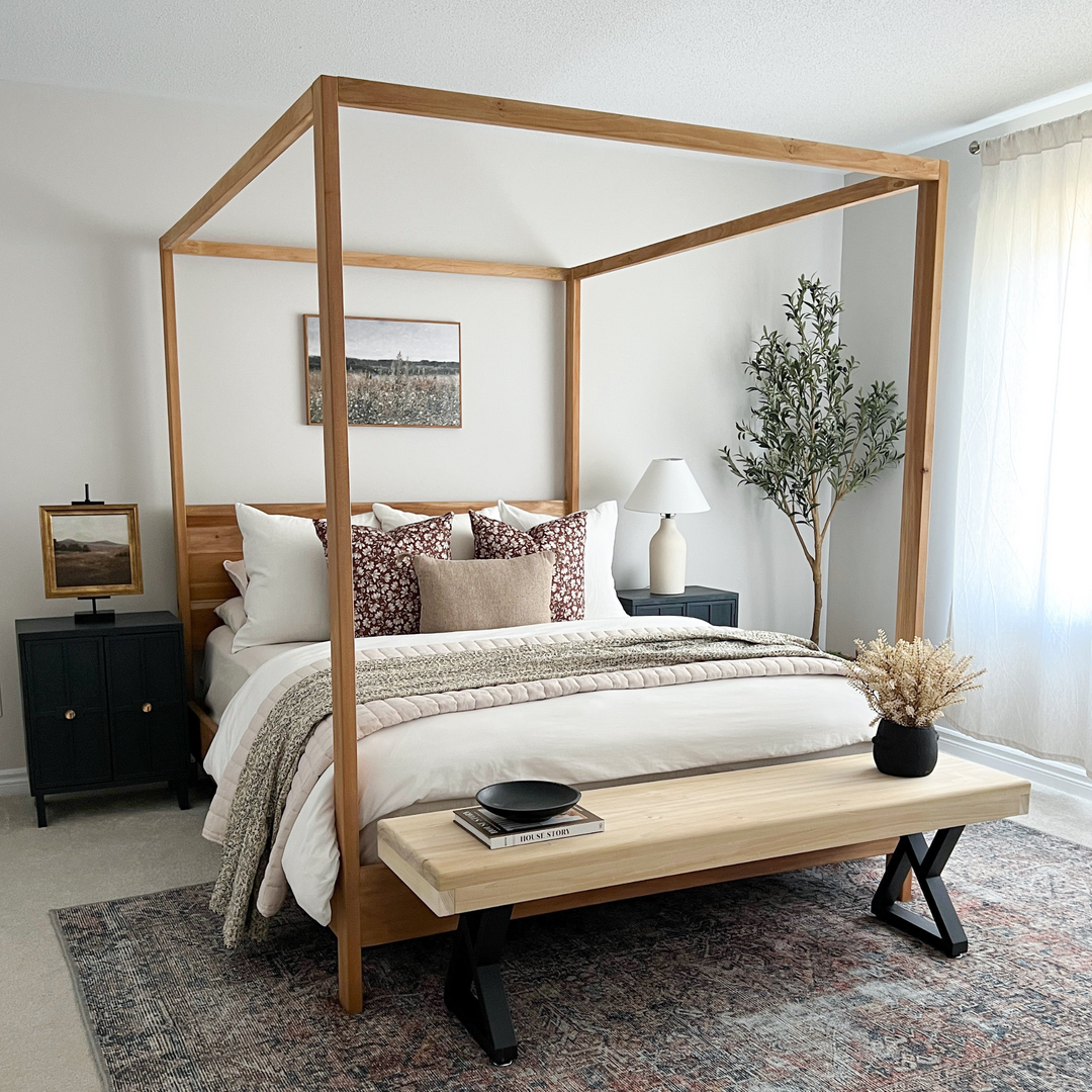 Wooden canopy bed in a bedroom with a bench and decor items.