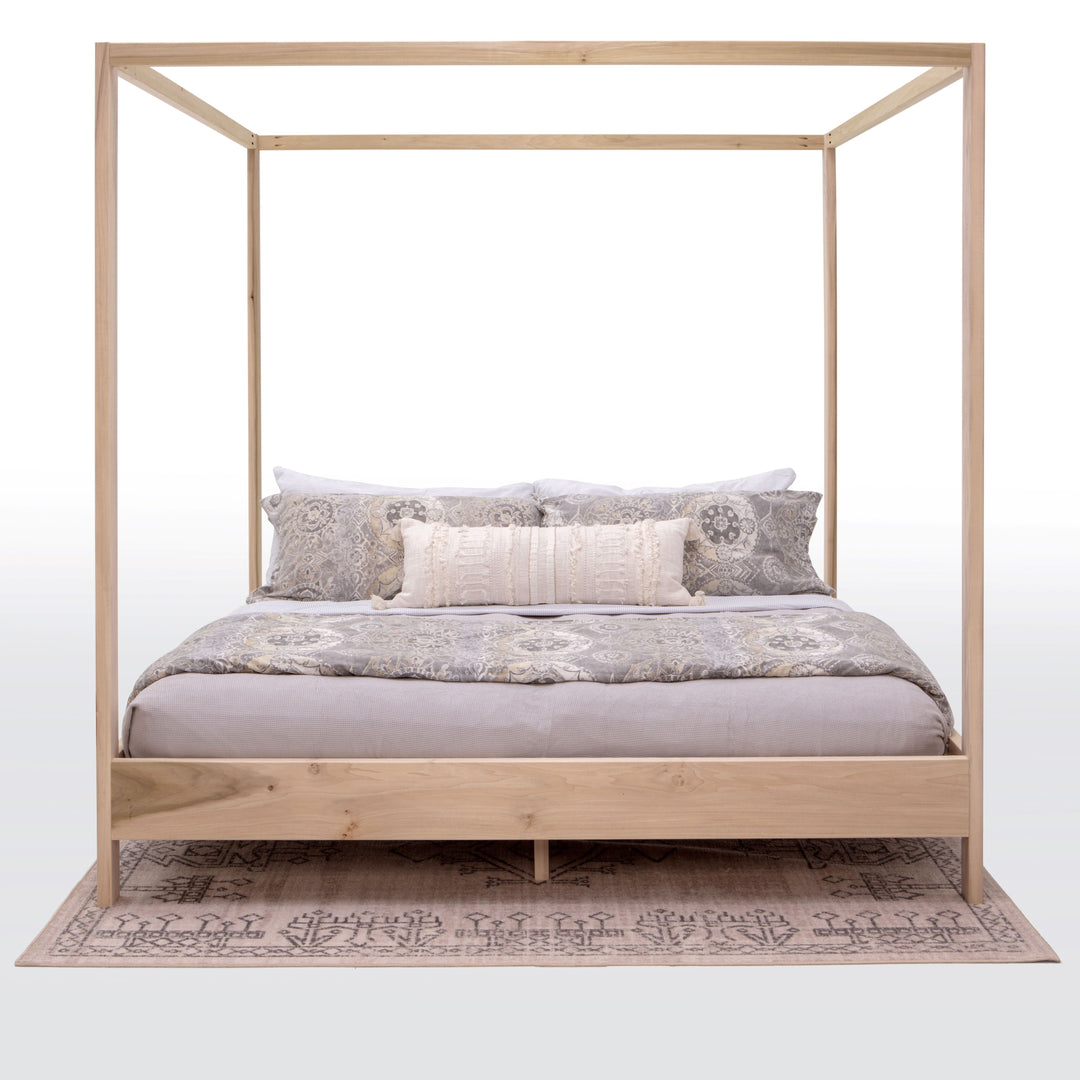 Wooden canopy bed with bedding on a white background