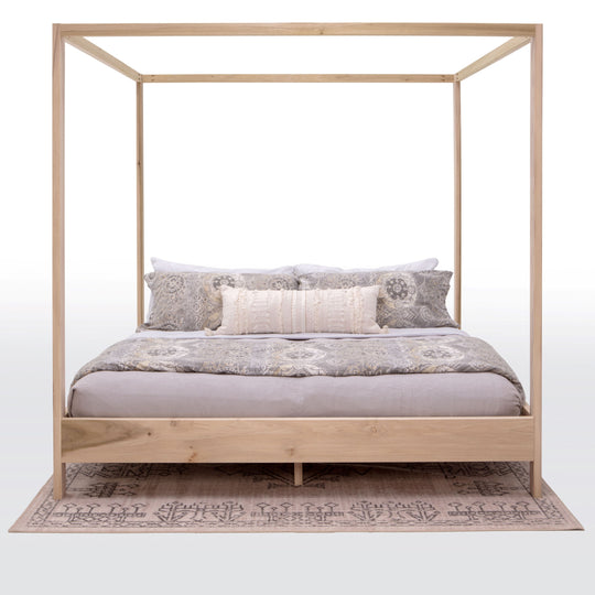 Wooden canopy bed with bedding on a white background