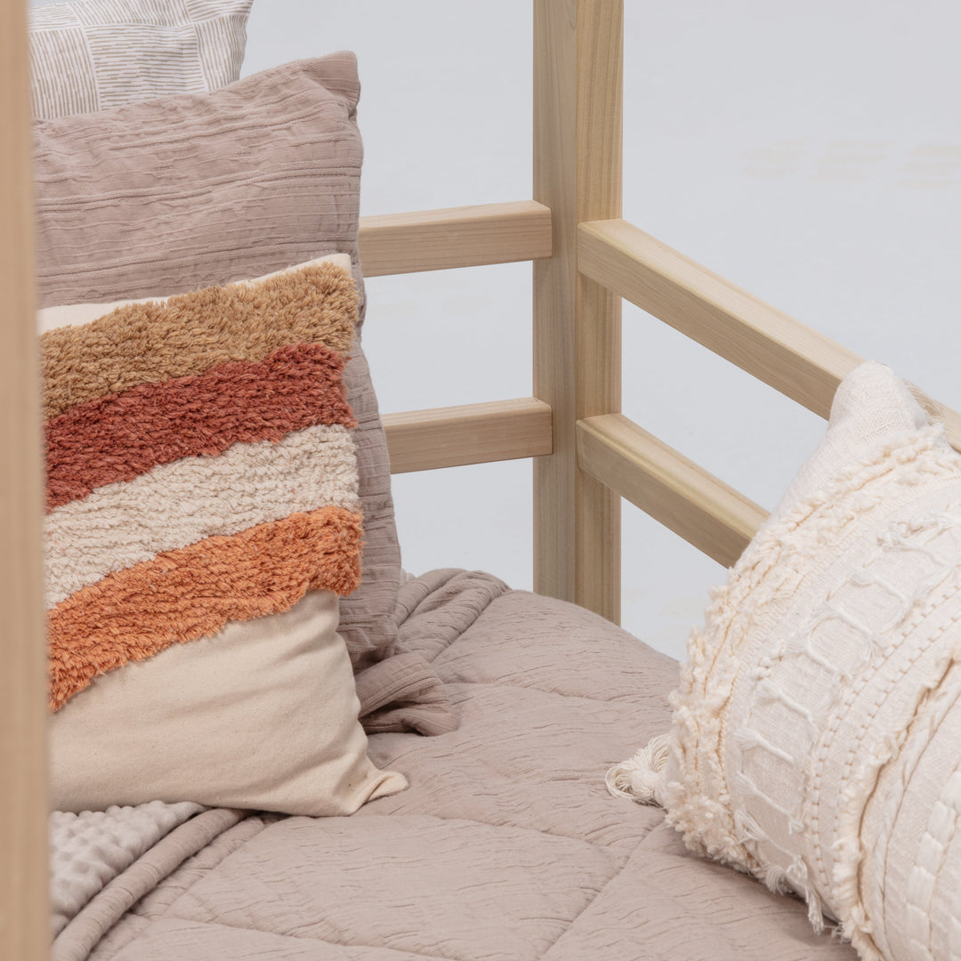 Cozy bed with textured pillows and a blanket against a light background