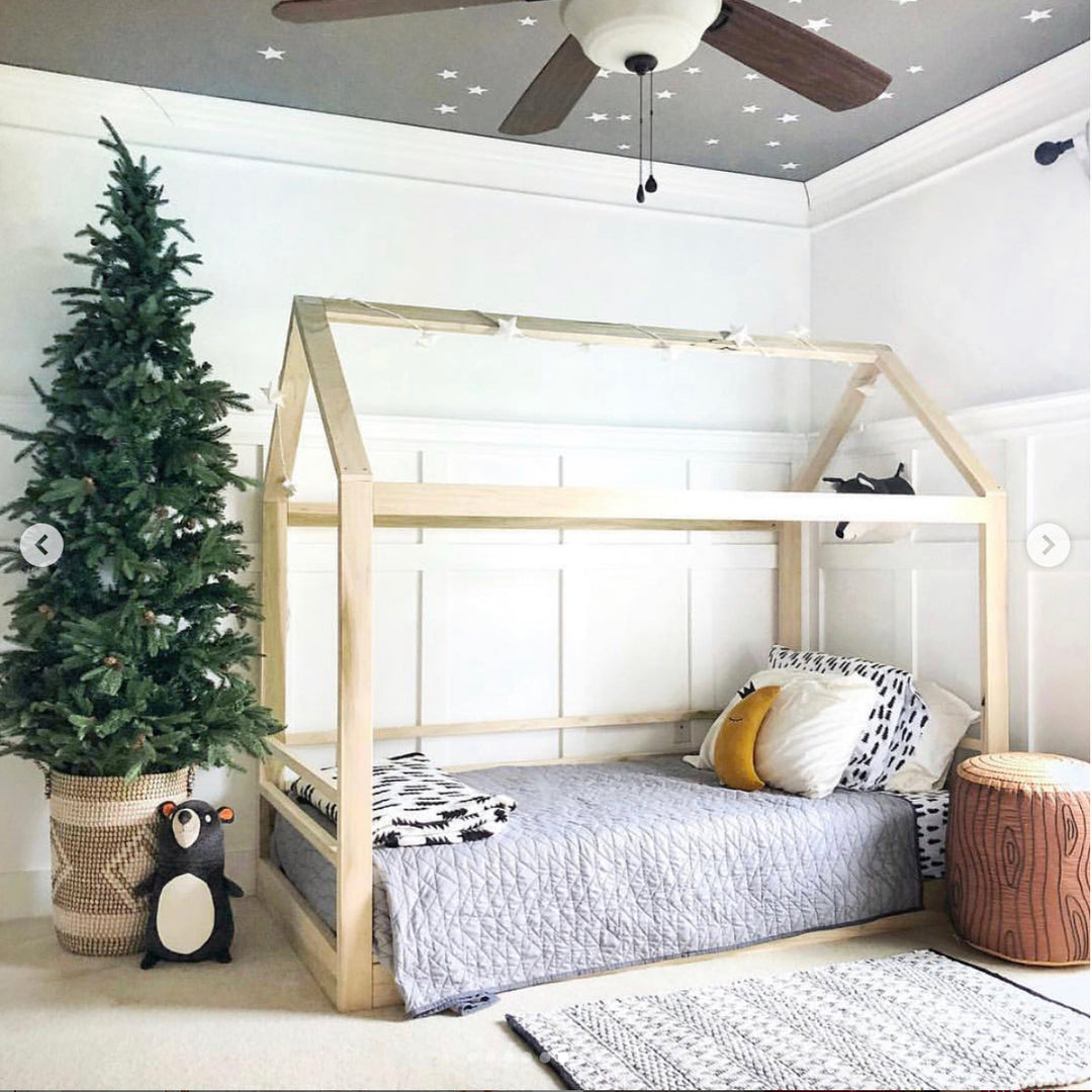 Children's bedroom with a wooden floor bed, Christmas tree, and decorative items.