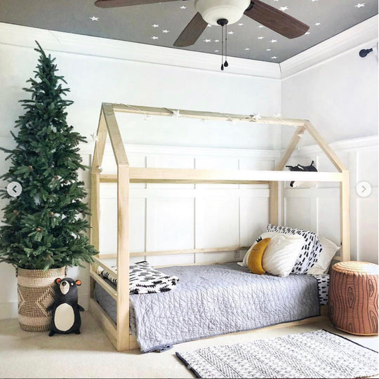 Children's bedroom with a wooden floor bed, Christmas tree, and decorative items.
