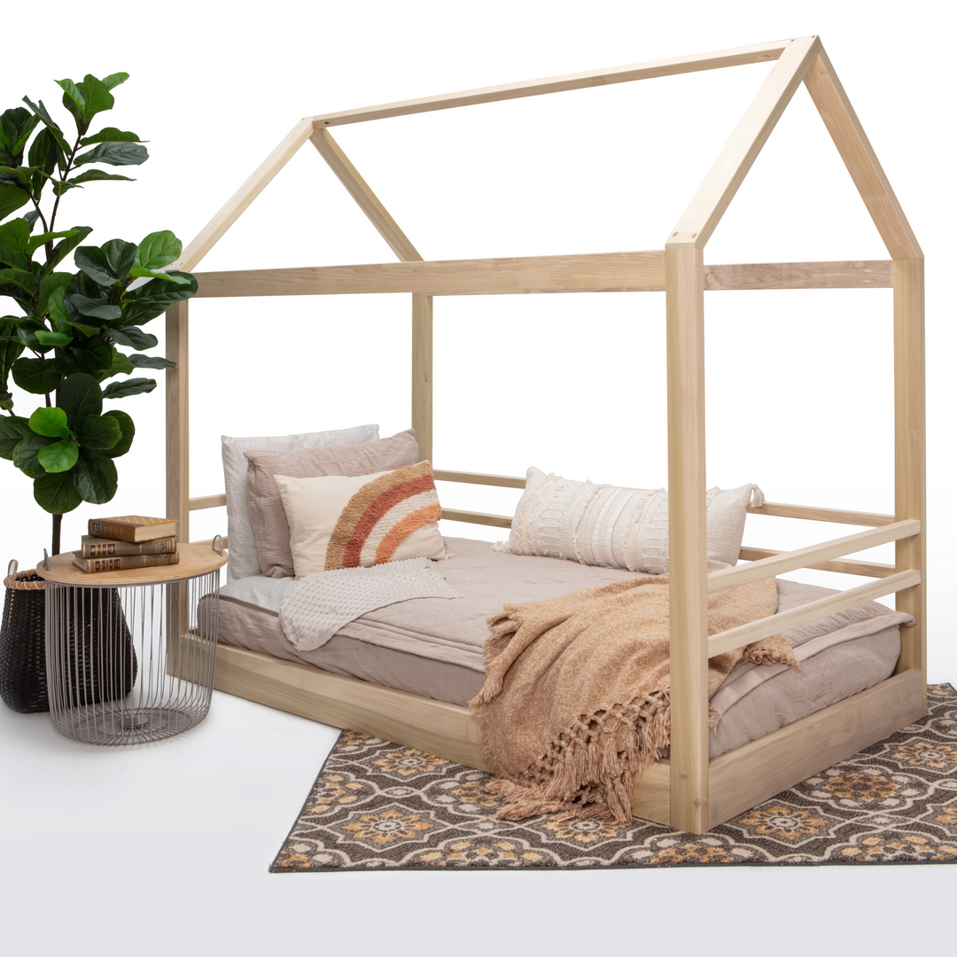 Wooden children's bed with bedding, side table, and plant on a white background