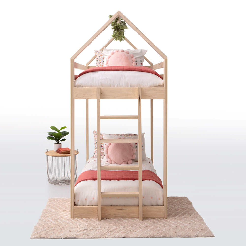 Wooden children's bed with pink bedding and pillows on a white background