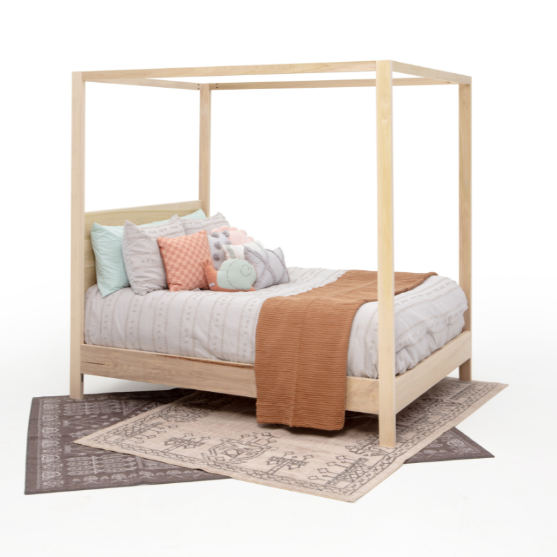Wooden canopy bed with bedding and pillows on a white background