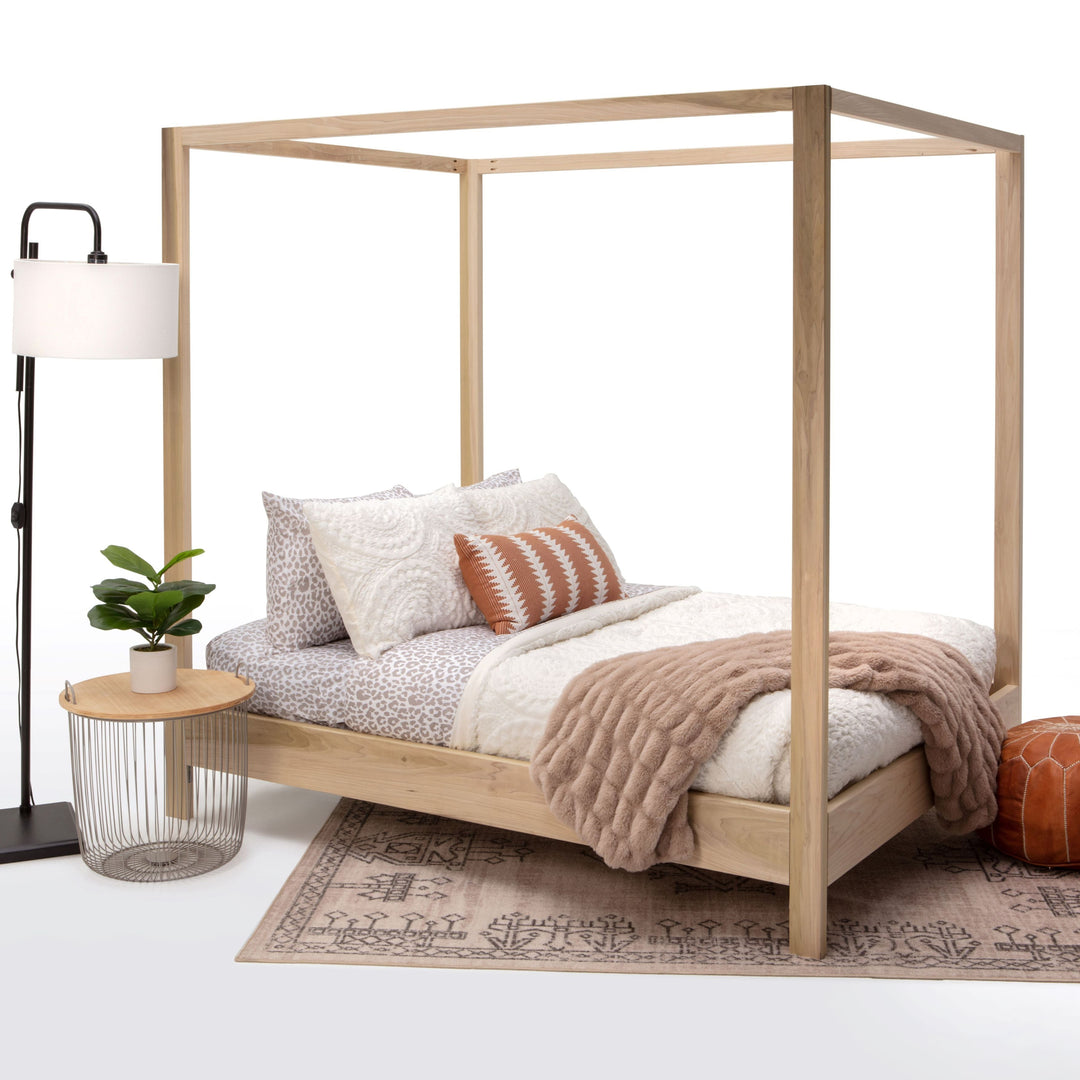 Wooden canopy bed with bedding and decor on a white background