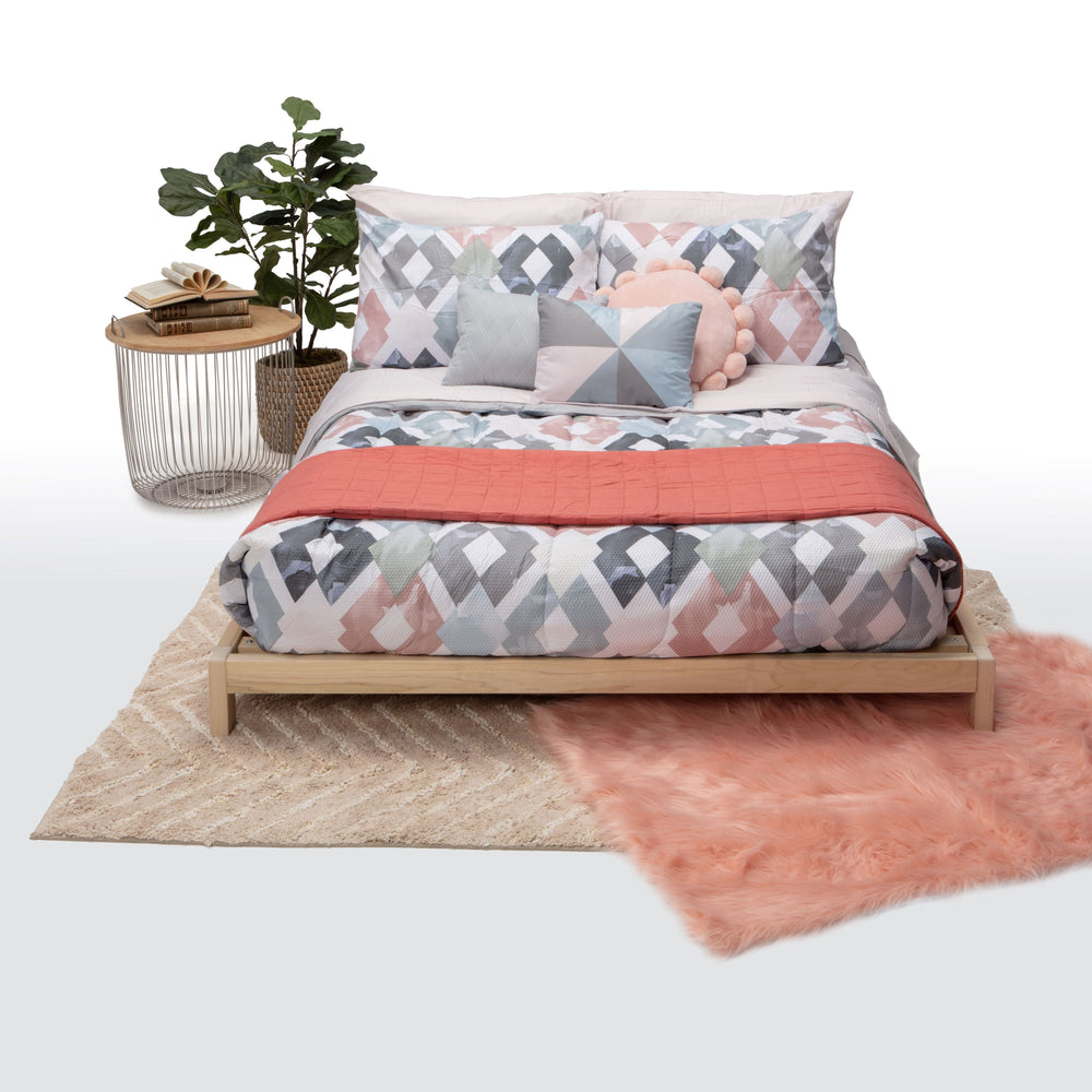 Bed with floral bedding and coral throw on a white background