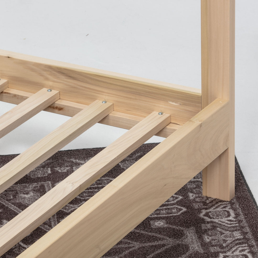 Wooden bed frame on a patterned rug with a white background