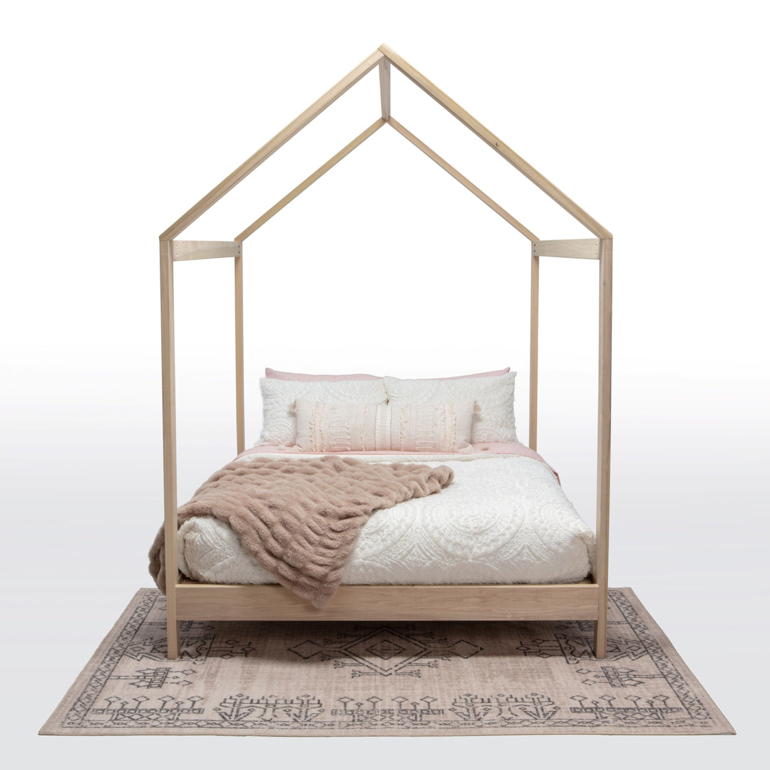 Wooden house-shaped bed with bedding on a white background