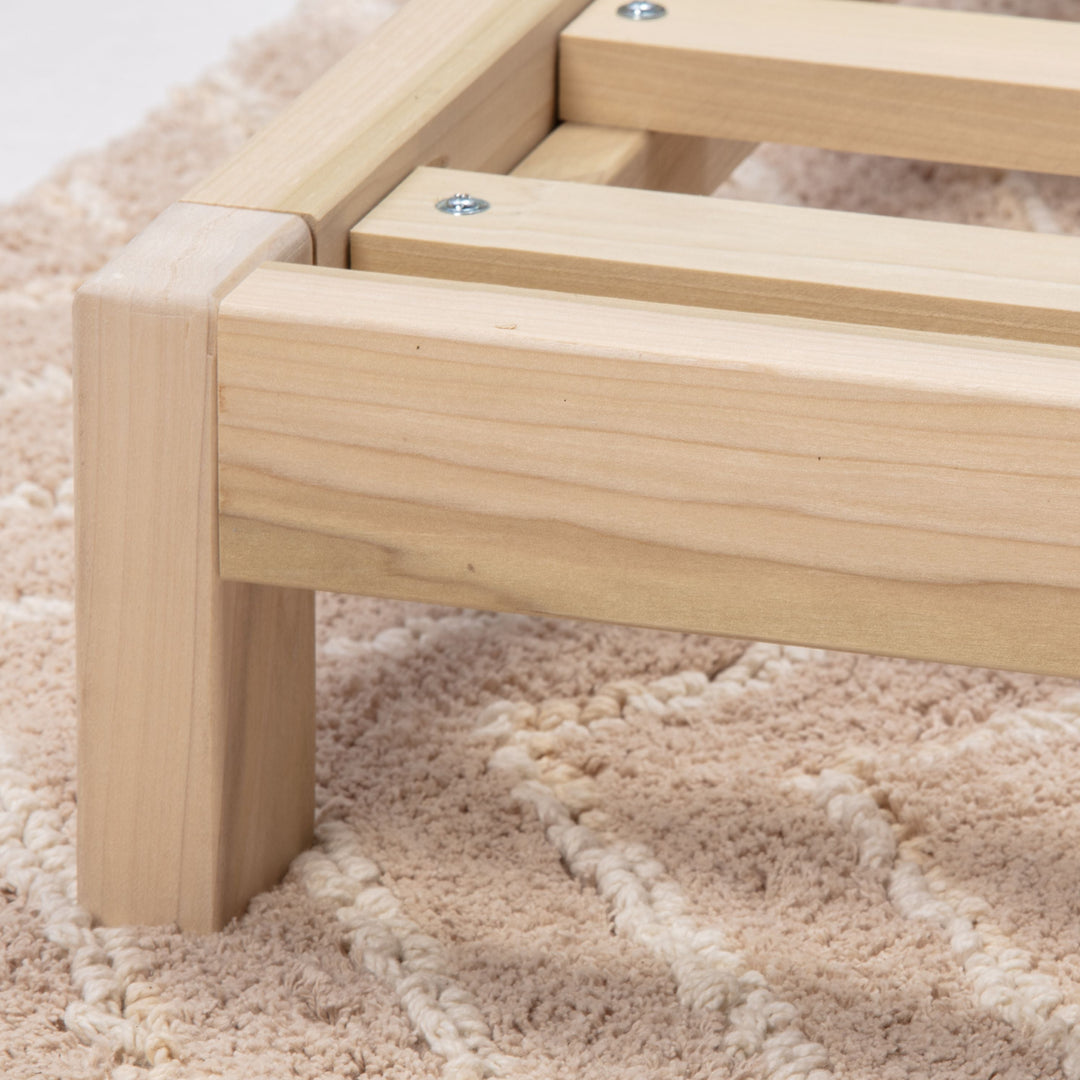 Wooden bed frame on a textured beige carpet