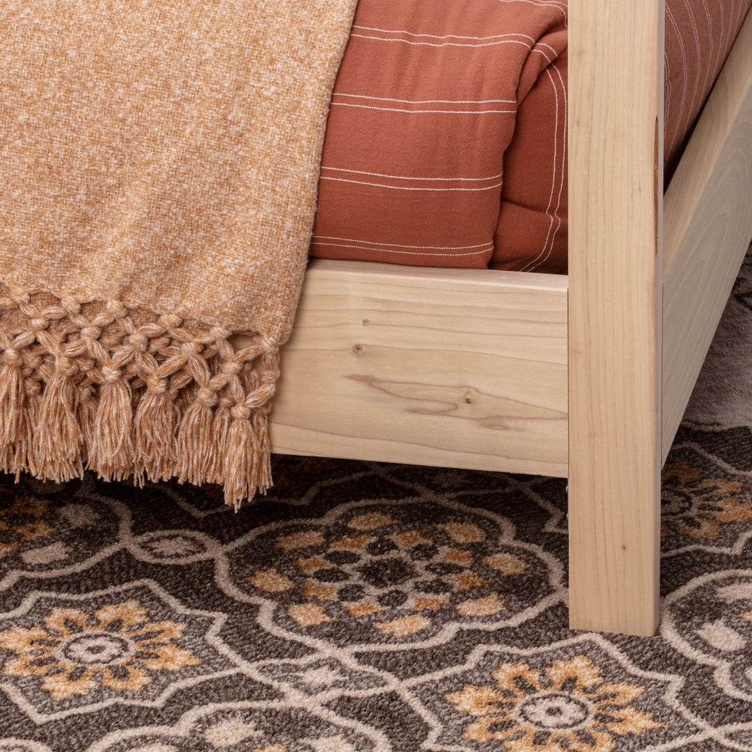 Patterned rug with a bed and wooden headboard in the background