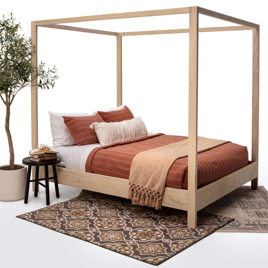 Wooden canopy bed with bedding and a plant on a white background