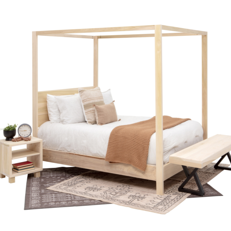 Wooden canopy bed with bedding and a side table in a bedroom setting