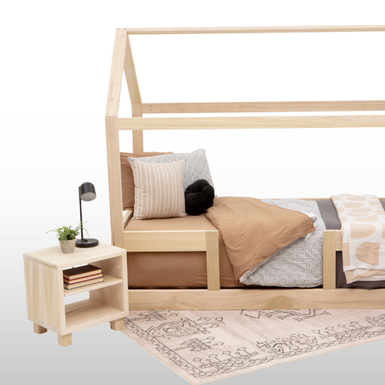 Wooden children's bed with bedding, nightstand, and rug on a white background