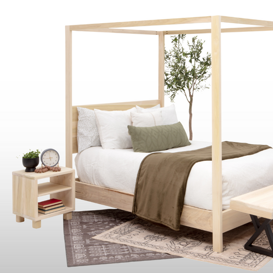 Wooden canopy bed with white bedding and a green throw blanket, nightstand with books and a clock, and small plant.