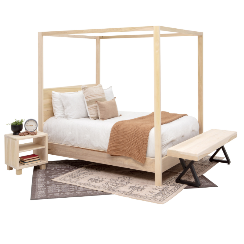 Wooden canopy bed with bedding and a side table in a bedroom setting
