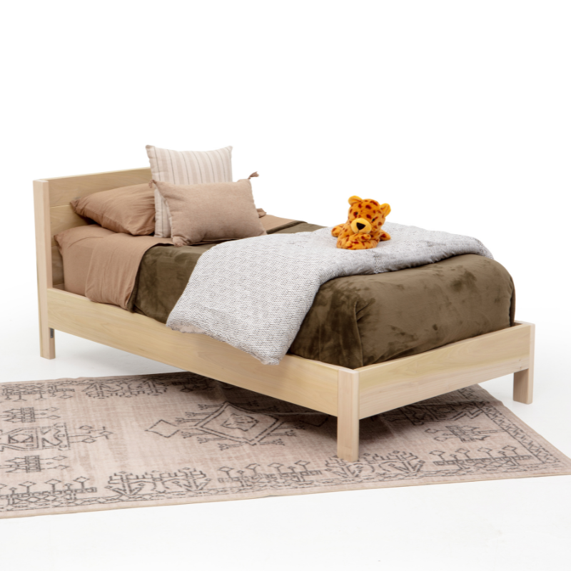 Bed with brown bedding and a teddy bear on a white background
