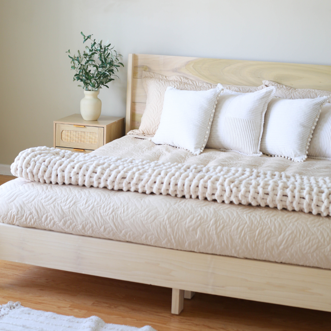 Neatly made bed with white bedding and pillows in a bedroom setting.