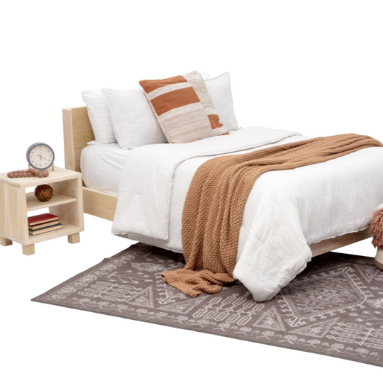 Bedroom setup with a bed, nightstand, and rug on a white background