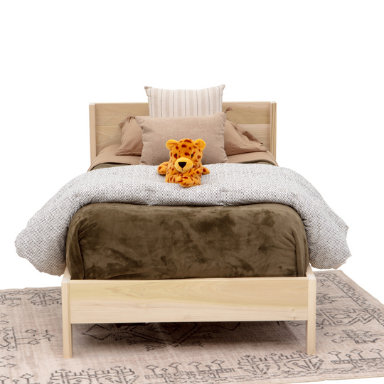 Wooden bed with bedding and a teddy bear on a white background