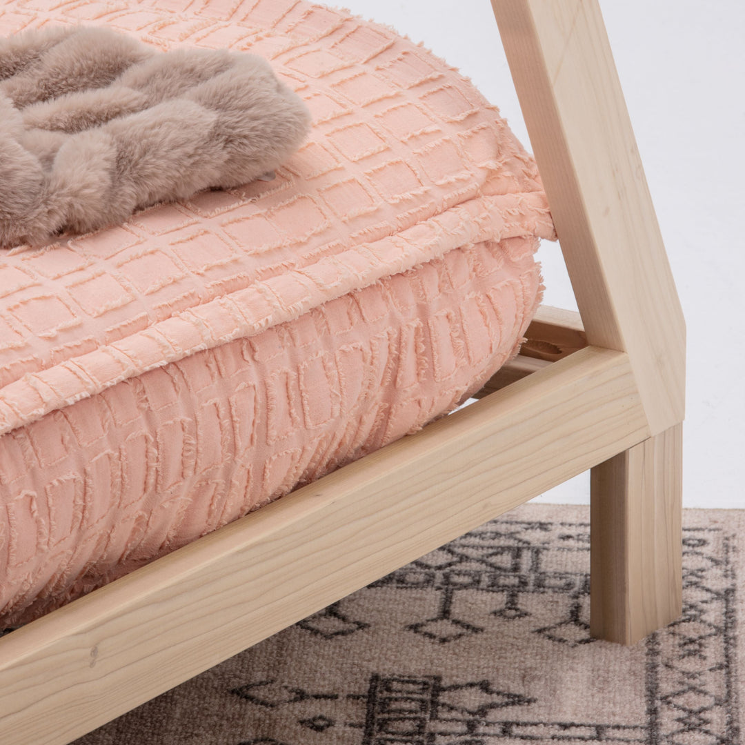 Wooden bed frame with pink textured bedspread and gray blanket on a white background