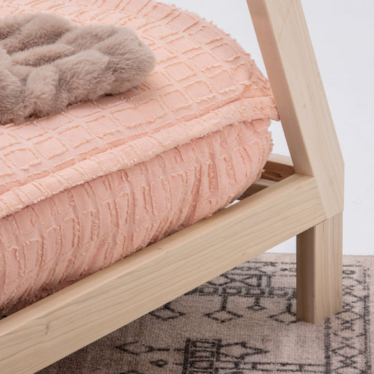 Wooden bed frame with pink textured bedspread and gray blanket on a white background